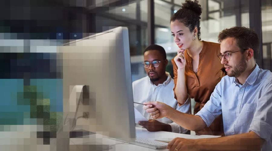 3 Personen arbeiten zusammen vor einem Monitor